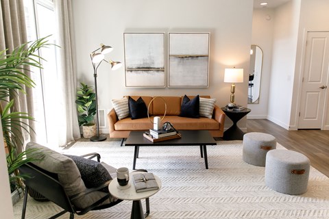 A living room with a couch, chair, and a table with a cup and a book on it.
