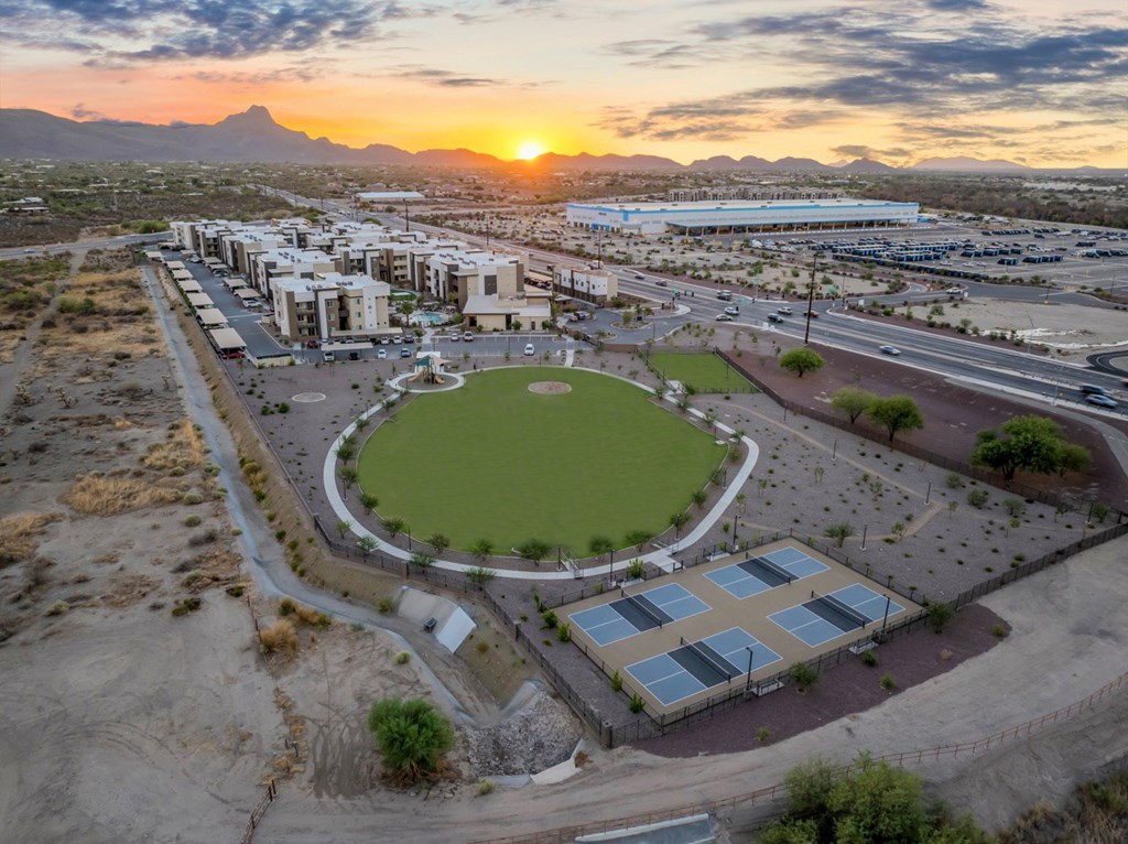 A sunset view of a sports field surrounded by buildings.