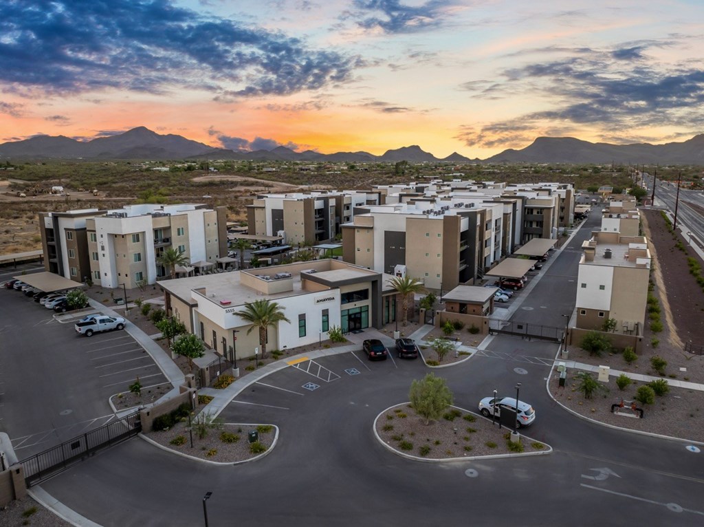 A sunset view of a parking lot with cars and buildings.