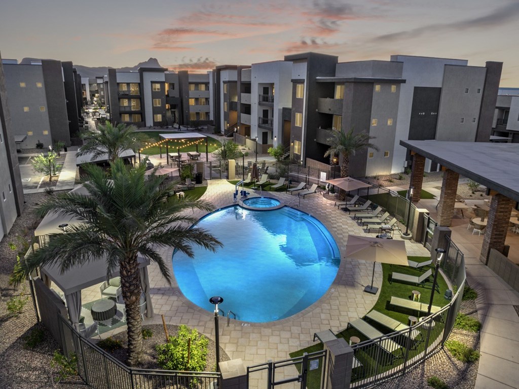 A swimming pool surrounded by palm trees and lounge chairs in a residential area.