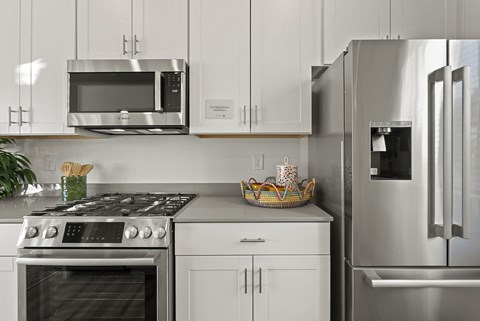 A modern kitchen with a stainless steel refrigerator, oven, and microwave.
