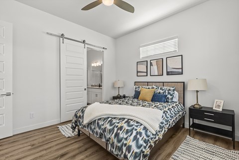 A bedroom with a bed, nightstand, and sliding door.