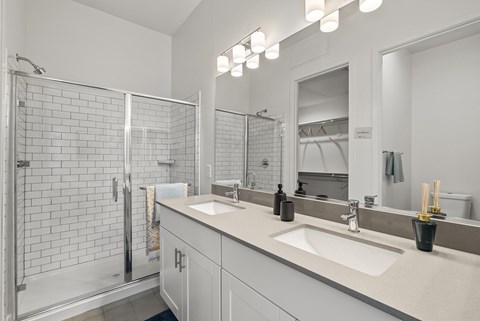 A bathroom with a white sink, mirror, and shower.