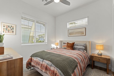 A bedroom with a bed, nightstand, and window.
