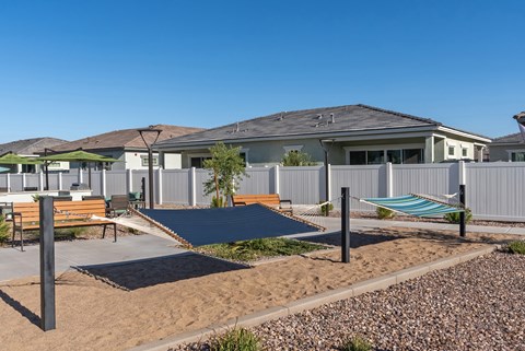 A playground area with a slide and a bench in front of a row of houses.