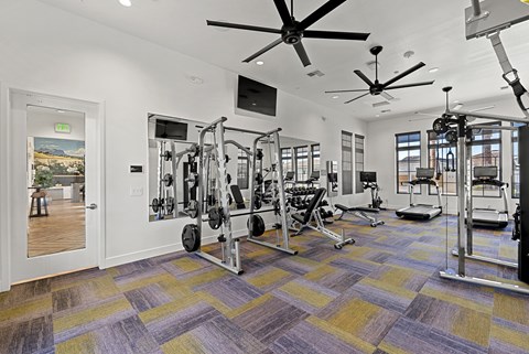 A spacious gym with a variety of equipment and a ceiling fan.