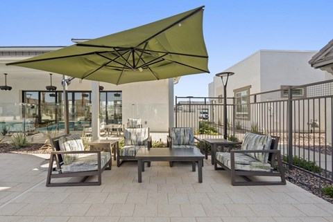 A patio with a table and chairs under a green umbrella.