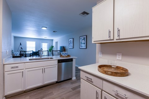 A kitchen with white cabinets and a wooden cutting board on the counter.