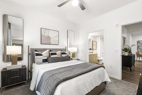A bedroom with a large bed and a ceiling fan.