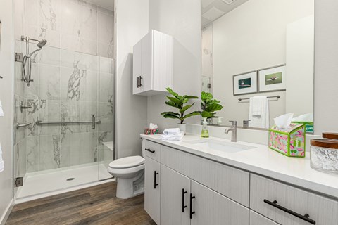 A bathroom with a toilet, sink, and a glass shower stall.