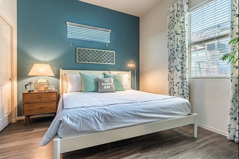 A bedroom with a bed, nightstand, and window.
