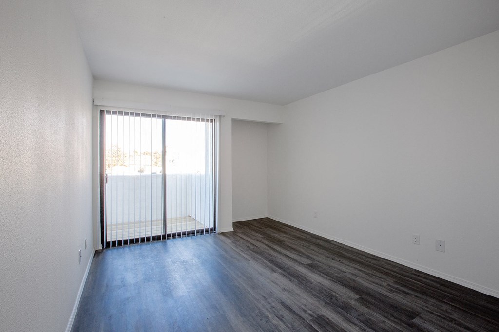 an empty living room with a sliding glass door and wood flooring