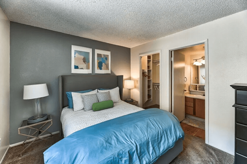 a bedroom with a bed and a bathroom with a mirror