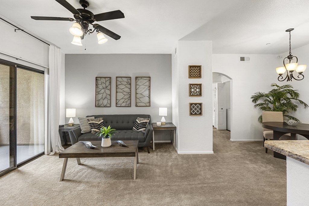 A living room with a black couch and a ceiling fan.