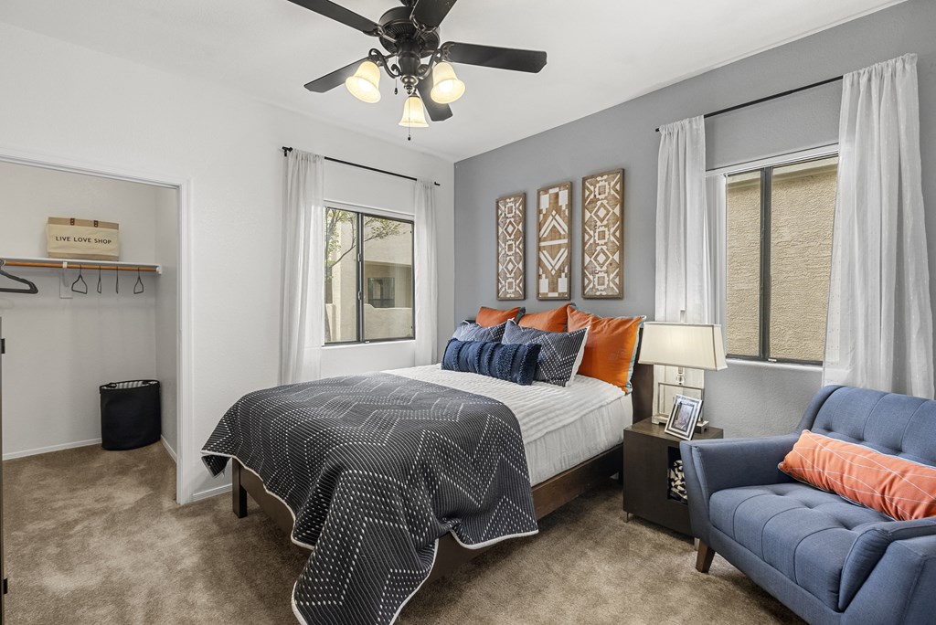 A bedroom with a bed, a couch, and a ceiling fan.