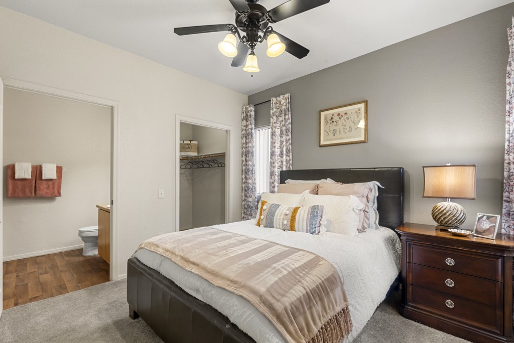 A bedroom with a large bed and a ceiling fan.