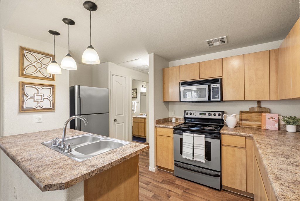 A kitchen with a black stove top oven and a granite counter top.