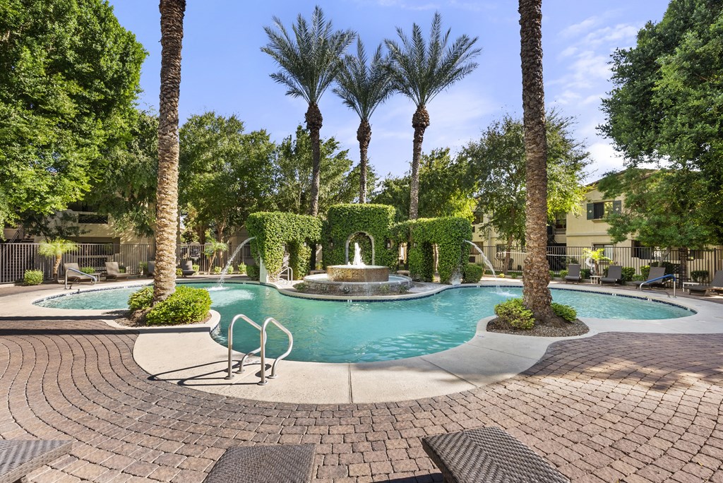 A pool surrounded by palm trees and bushes.