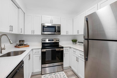 A modern kitchen with white cabinets and stainless steel appliances.