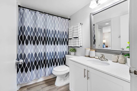 A bathroom with a white toilet and a shower curtain with a diamond pattern.