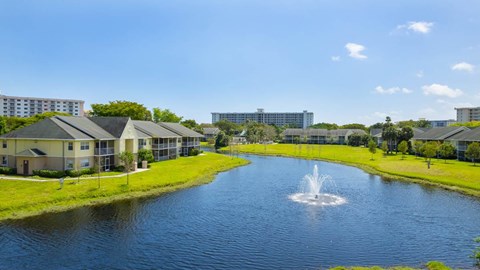 A fountain in the middle of a lake surrounded by buildings.