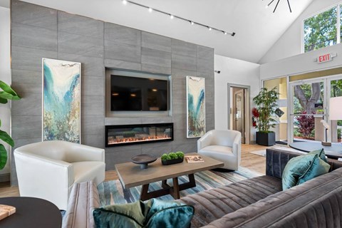 A modern living room with a grey couch and a fireplace.