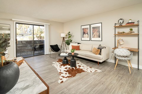 A living room with a white couch, a black chair, and a cowhide rug.