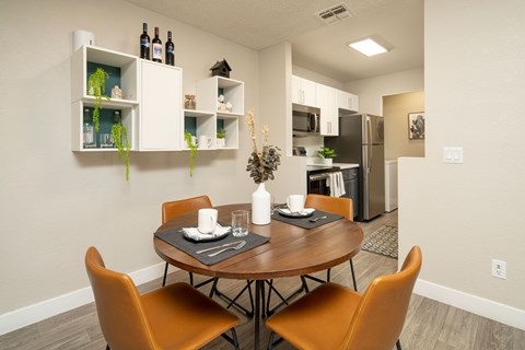 A dining room with a table set for two and orange chairs.
