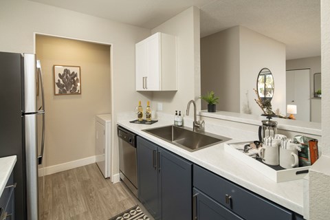 A kitchen with a black refrigerator and a sink with a silver faucet.