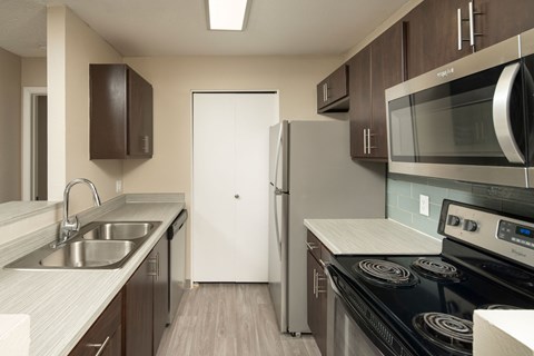 A modern kitchen with dark brown cabinets and stainless steel appliances.
