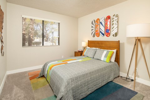 A bedroom with a bed, pillows, and a colorful rug.