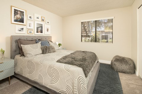 A bedroom with a large bed and a window with blinds.