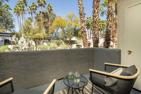 A patio with a table and chairs overlooking a garden.