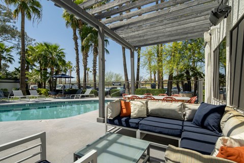 A patio with a couch and a table is covered by a roof.
