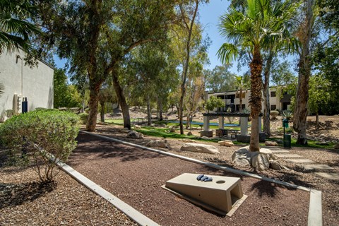 A playground with a slide and a sandbox in the middle of a garden.
