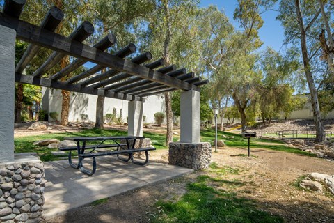 A wooden pergola with a picnic table underneath it.