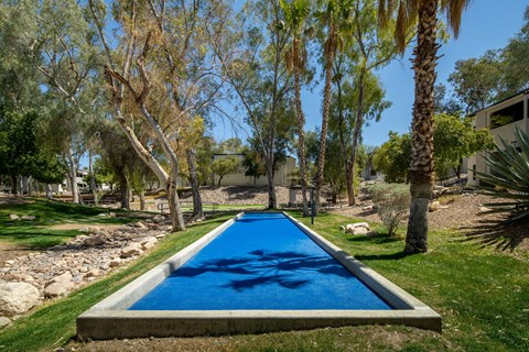 A blue rectangular pool surrounded by trees and grass.
