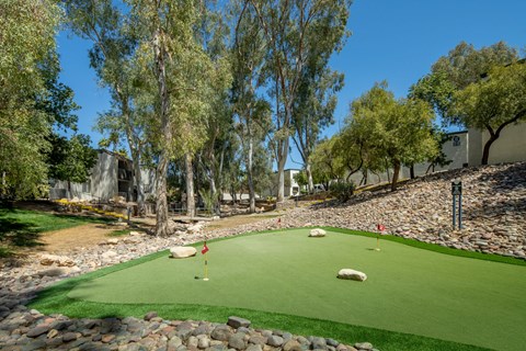 A miniature golf course with a red flag on the green.