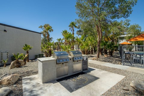 A BBQ grill is in the middle of a gravel area.