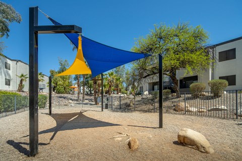 A playground with a blue canopy and a yellow slide.