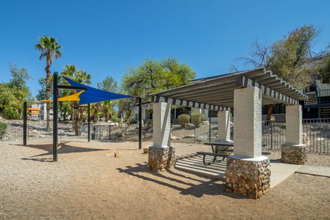 A playground with a blue canopy and a swing set.