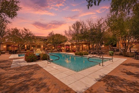 A pool surrounded by trees and a building in the background.