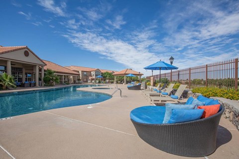 A pool area with a blue umbrella and a round wicker chair.