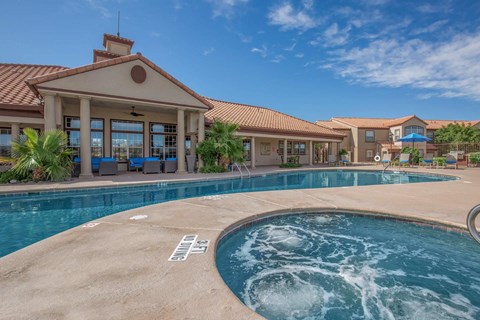A pool with a hot tub in front of a house.