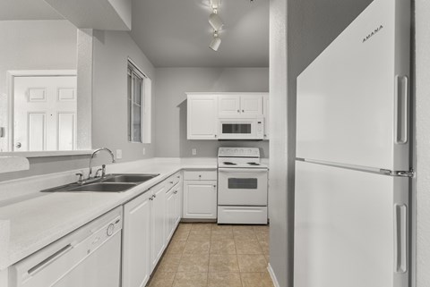 A white kitchen with a refrigerator on the right.