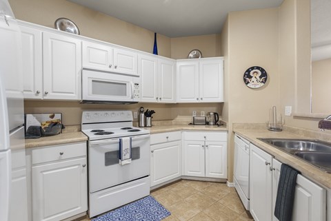 A kitchen with white cabinets and appliances.