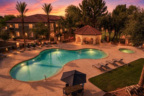 A large outdoor swimming pool surrounded by lounge chairs and umbrellas.