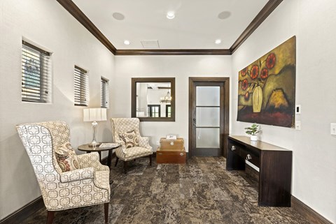 A living room with a patterned carpet and a painting on the wall.
