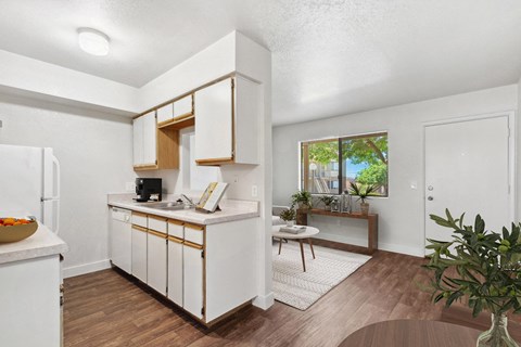 a kitchen with white cabinets and a table and a window