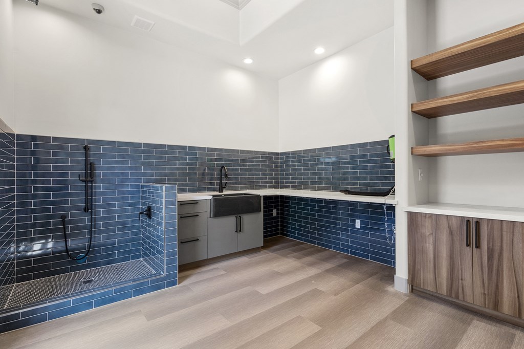A modern kitchen with a blue tile backsplash and wooden flooring.